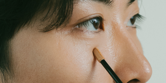 Man applying concealer to his under-eye area