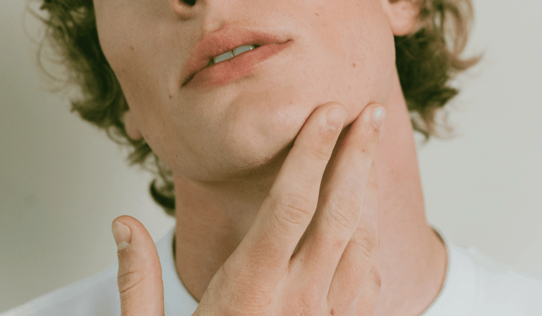 A man touching his jaw after applying Kint nail strengthener